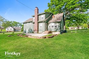 Grandview house for rent - A green house with a brick chimney is surrounded by a grassy lawn.