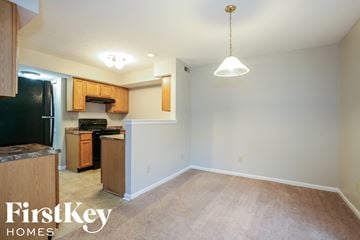 Indianapolis house for rent - a kitchen and living room with a carpeted floor and wood cabinets