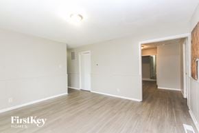 Indianapolis house for rent - A spacious room with wooden flooring and white walls, with a doorway leading to another room.