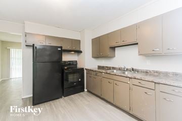 Indianapolis house for rent - A kitchen with a black fridge and beige cabinets.