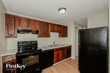 Indianapolis house for rent - A kitchen with wooden cabinets and a black refrigerator.
