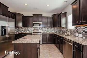 Charlotte house for rent - a kitchen with dark cabinets and granite counter tops and stainless steel appliances
