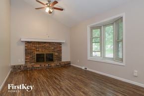 Parkville house for rent - A room with a fireplace and a ceiling fan.