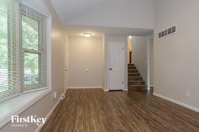 Parkville house for rent - A room with wooden floors and a staircase leading to another room.
