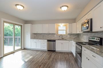 Parkville house for rent - A kitchen with white cabinets and a wooden floor.