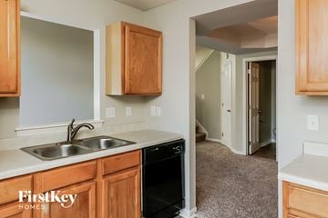 Indianapolis house for rent - a kitchen with a sink and wooden cabinets and a door to a hallway