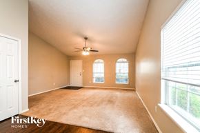 Zionsville house for rent - A spacious room with a carpeted floor, a ceiling fan, and a large window with blinds.