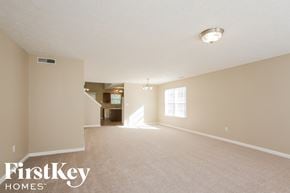 Indianapolis house for rent - A spacious empty room with a carpeted floor and a window letting in natural light.