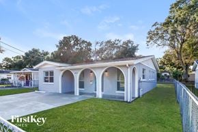 Tampa house for rent - a blue and white house with a porch and a lawn