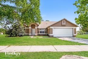 Orlando house for rent - A house with a brown roof and a white garage door is surrounded by greenery.