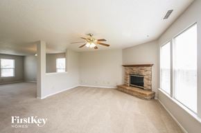 Mccordsville house for rent - an empty living room with a fireplace and a ceiling fan