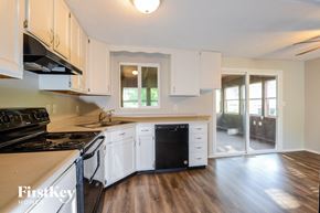 Indianapolis house for rent - a kitchen with white cabinets and black appliances and a sliding glass door