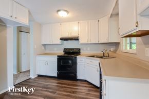 Indianapolis house for rent - an empty kitchen with white cabinets and black appliances