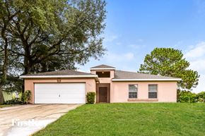 North Port house for rent - a pink house with a lawn and a garage