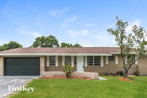 Plantation house for rent - A house with a garage door and a tree in front.