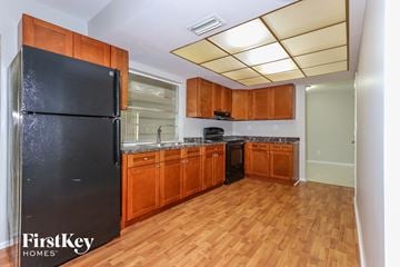 Plantation house for rent - A kitchen with wooden cabinets and a black fridge.