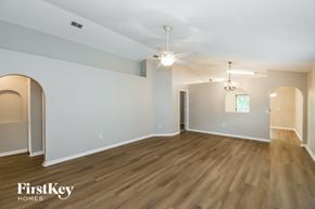 Jacksonville house for rent - A spacious room with wooden floors and a ceiling fan.