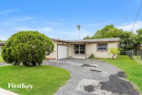 Sunrise house for rent - A house with a driveway and a tree in front of it.