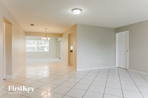 Sunrise house for rent - A spacious room with white tiled floors and a chandelier hanging from the ceiling.