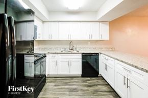Hialeah house for rent - an empty kitchen with white cabinets and black appliances