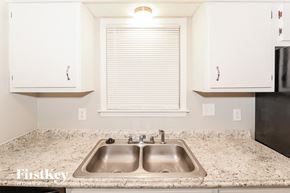 Bartlett house for rent - a kitchen with white cabinets and a sink and a window