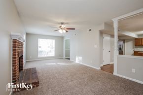 Charlotte house for rent - A spacious living room with a brick fireplace and a ceiling fan.