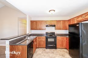 Cordova house for rent - a kitchen with wood cabinets and black appliances and a sink