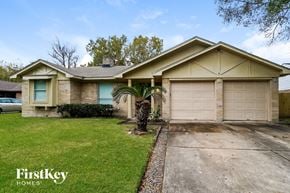 Houston house for rent - A house with a garage and a tree in front of it.