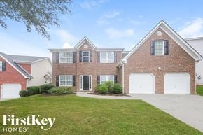 Atlanta house for rent - a brick house with white garage doors and a lawn