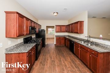 Atlanta house for rent - a kitchen with wooden cabinets and granite counter tops and black appliances