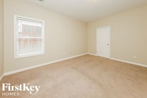 Atlanta house for rent - a bedroom with beige carpet and a window and a white door