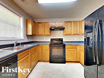 Lithonia house for rent - a kitchen with wooden cabinets and a sink and a refrigerator