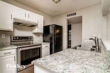 Fort Worth house for rent - a kitchen with granite counter tops and black appliances