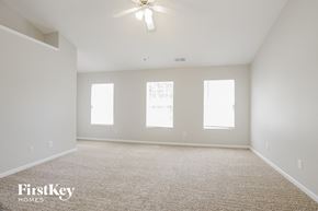Charlotte house for rent - a spacious living room with white walls and a ceiling fan