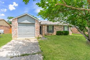 Fort Worth house for rent - a small brick house with a gray garage door and a lawn