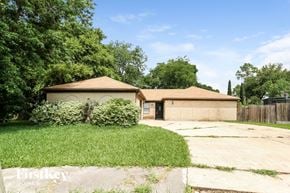 Spring house for rent - A house with a brown roof and a garage is surrounded by greenery.