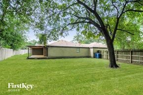 Spring house for rent - A tree stands in a grassy yard in front of a house.