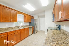 Lakeland house for rent - a kitchen with wooden cabinets and granite counter tops and a stainless steel refrigerator
