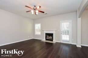 Braselton house for rent - A spacious room with a fireplace and a ceiling fan.