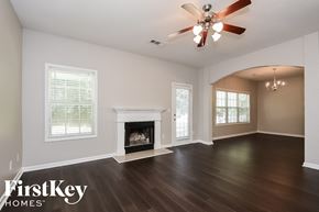 Braselton house for rent - A spacious room with a fireplace and a ceiling fan.