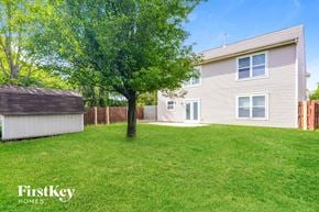 Avon house for rent - A tree stands in a grassy yard in front of a house.