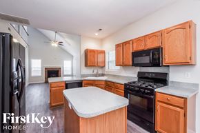 Charlotte house for rent - a kitchen with wood cabinets and black appliances and a white counter top
