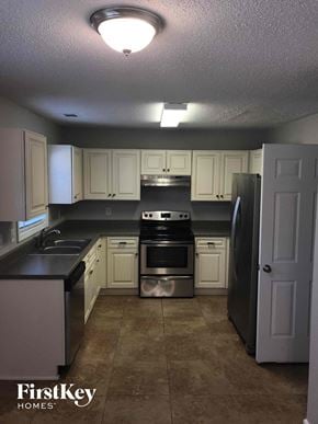 Lithonia house for rent - a kitchen with white cabinets and stainless steel appliances