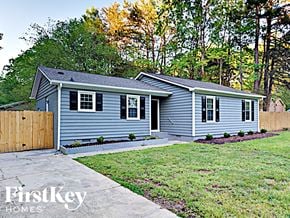 Charlotte house for rent - a small blue house with a yard and a wooden fence