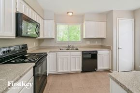 Richmond house for rent - a kitchen with white cabinets and black appliances
