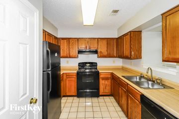 Memphis house for rent - a kitchen with wooden cabinets and black appliances and a sink