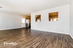Phoenix house for rent - A spacious room with wooden flooring and white walls, with a refrigerator and a chandelier visible.