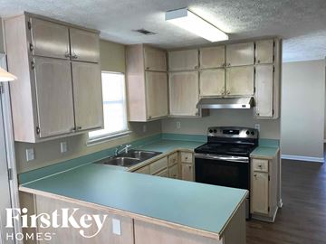 Riverdale house for rent - a kitchen with white cabinets and green counter tops