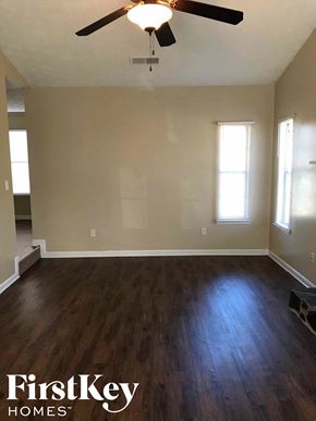 Riverdale house for rent - an empty living room with wood floors and a ceiling fan