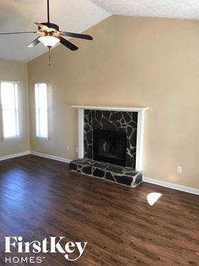Riverdale house for rent - an empty living room with a fireplace and a ceiling fan